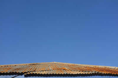 Low angle view of building roof against clear blue sky