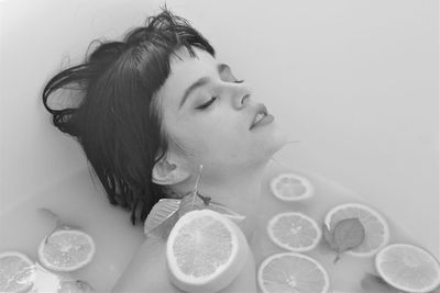 Close-up of woman taking bath with fruits in bathtub