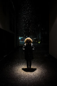 Person wearing warm clothing standing on city street at night