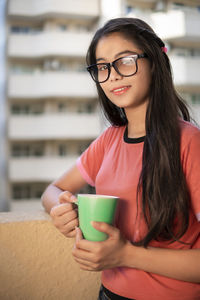 Portrait of smiling young woman holding coffee cup