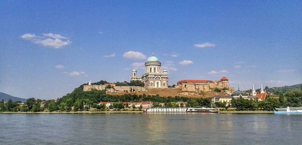 Buildings at waterfront against cloudy sky