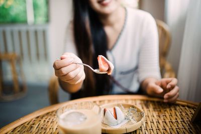 Midsection of woman holding ice cream on table