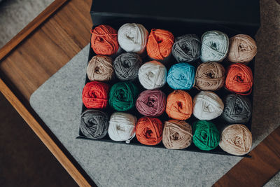Overhead shot of a box full of different coloured skeins of amigurumi cotton yarn, selective focus.