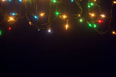 Low angle view of illuminated christmas lights against black background