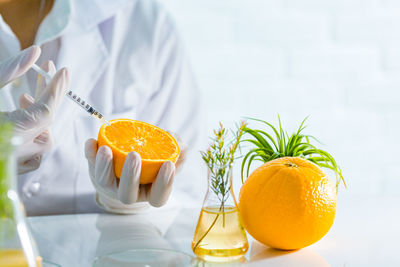 Education background, scientist is holding a orange and sampling chemical from organic natural, 