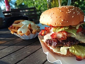 Close-up of burger in plate on table with fries in background