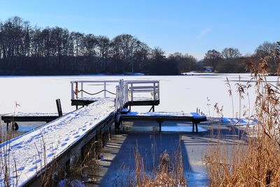 Snow covered wooden jetty at a frozen lake on a sunny day in germany