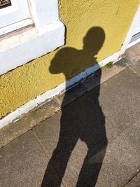 Shadow of man on street by building