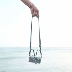 Man holding umbrella against sea against clear sky