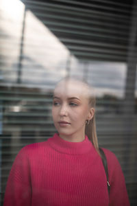 Portrait of woman standing against red wall