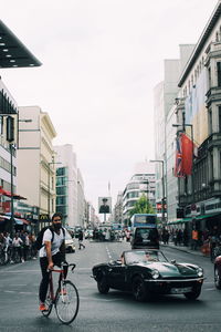 Man riding bicycle on city street against sky