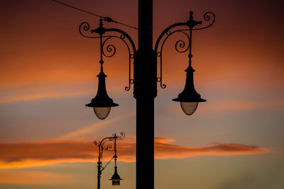 Silhouette street light against orange sky
