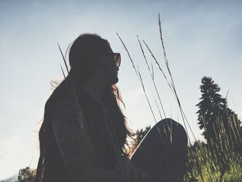 Low angle view of young woman against clear sky