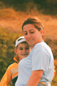 Low angle portrait of happy boy standing with mother looking down