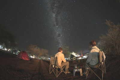 Rear view of couple sitting on chair at night