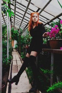 Portrait of woman standing by flower plants