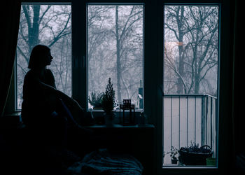 Woman sitting by window at home