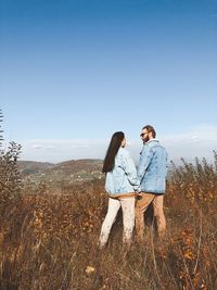 Young couple standing on land against sky