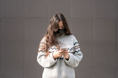 Midsection of woman holding umbrella standing against wall