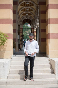 Full length portrait of young man standing on steps