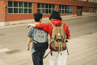 Rear view of friends walking on street in city