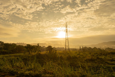 Electricity pylon on field against sky during sunset