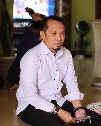 Portrait of man holding camera while sitting at home
