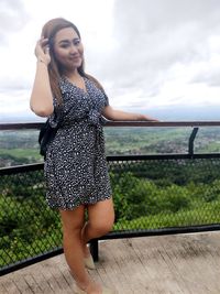 Portrait of beautiful woman standing against sky