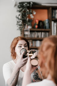 Portrait of woman holding camera at home