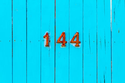 House number 144 on a turquoise wooden door 