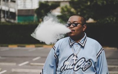 Man exhaling smoke while standing in city