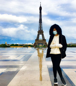 Full length of woman standing with tower in background