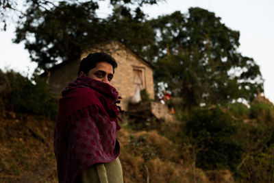 Man wearing shawl and standing outside home 