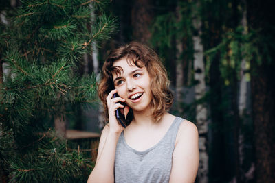 Beautiful teenager girl talking by phone at the forest.