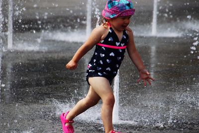 Full length of woman with arms raised in rain