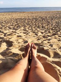 Low section of person relaxing on sand at beach