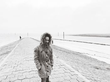 Woman standing by sea against sky during winter