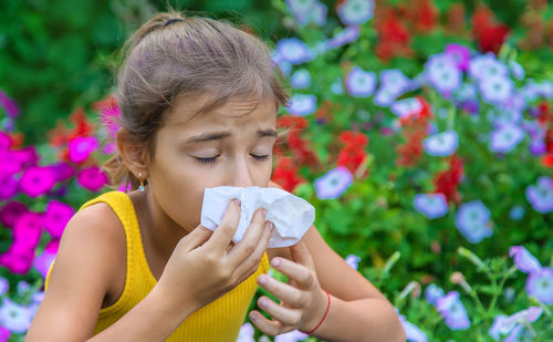 Girl sneezing with tissue on mouth