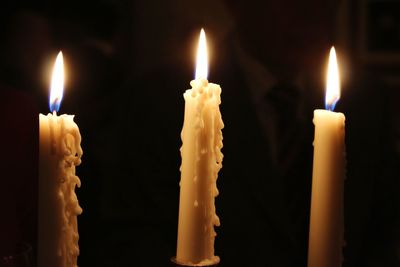 Close-up of burning candles in darkroom