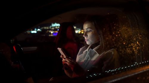 Serious businesswoman using smartphone in driver sits while riding from work