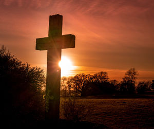 Cross on field against sky during sunset