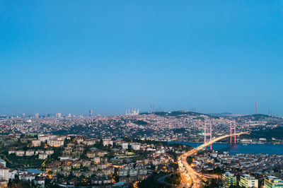 Illuminated cityscape against clear blue sky