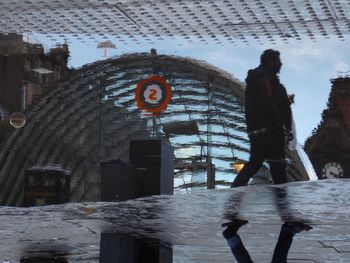 Man walking on street by buildings in city during winter