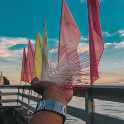 Midsection of person holding umbrella by sea against sky