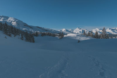 A picturesque landscape view of the snowcapped french alps mountains with a hiking path in the snow