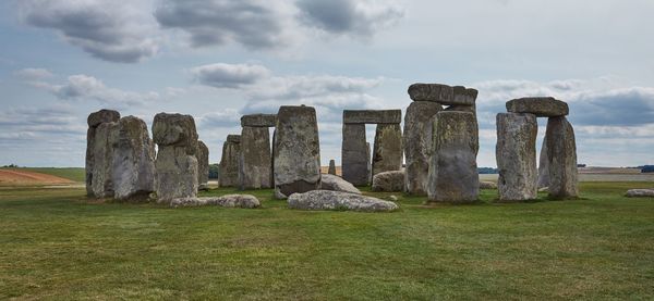 Neothlic stone circle on field against cloudy sky