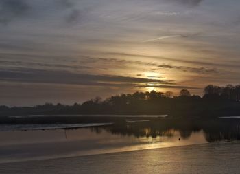 Reflection of trees in water at sunset