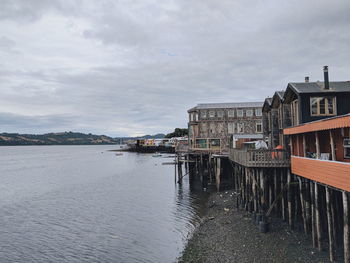 Buildings by river against sky