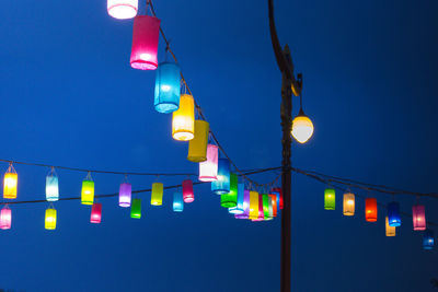 Low angle view of illuminated lights against clear blue sky