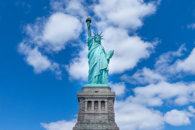 Low angle view of statue of liberty against cloudy sky